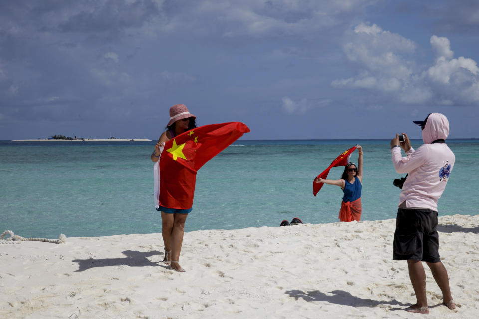 FILE - In this Sept. 14, 2014, file photo, Chinese tourists take souvenir photos with the Chinese national flag as they visit Quanfu Island, one of Paracel Islands of Sansha prefecture of southern China's Hainan province in the South China Sea. China recently announced the establishment of two districts to administer two disputed groups of islands and reefs in the South China Sea to fortify its claim to virtually the entire waterway, among the world’s busiest. One district reportedly covers the Paracel islands and the other has jurisdiction over the Spratlys, the most hotly contested territory in the strategic waters where the Philippines has a presence on at least nine islands and islets and where China has built fortified man-made islands to assert its own claim. (AP Photo/Peng Peng, File)