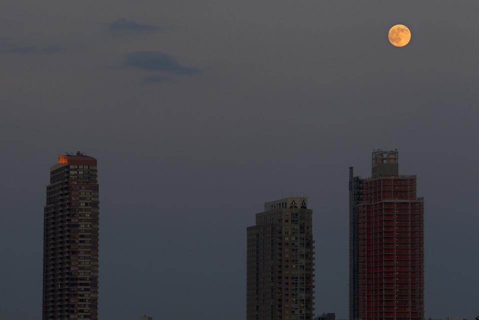 The moon is pictured one day ahead of the Supermoon phenomenon as it rises over buildings in Long Island City