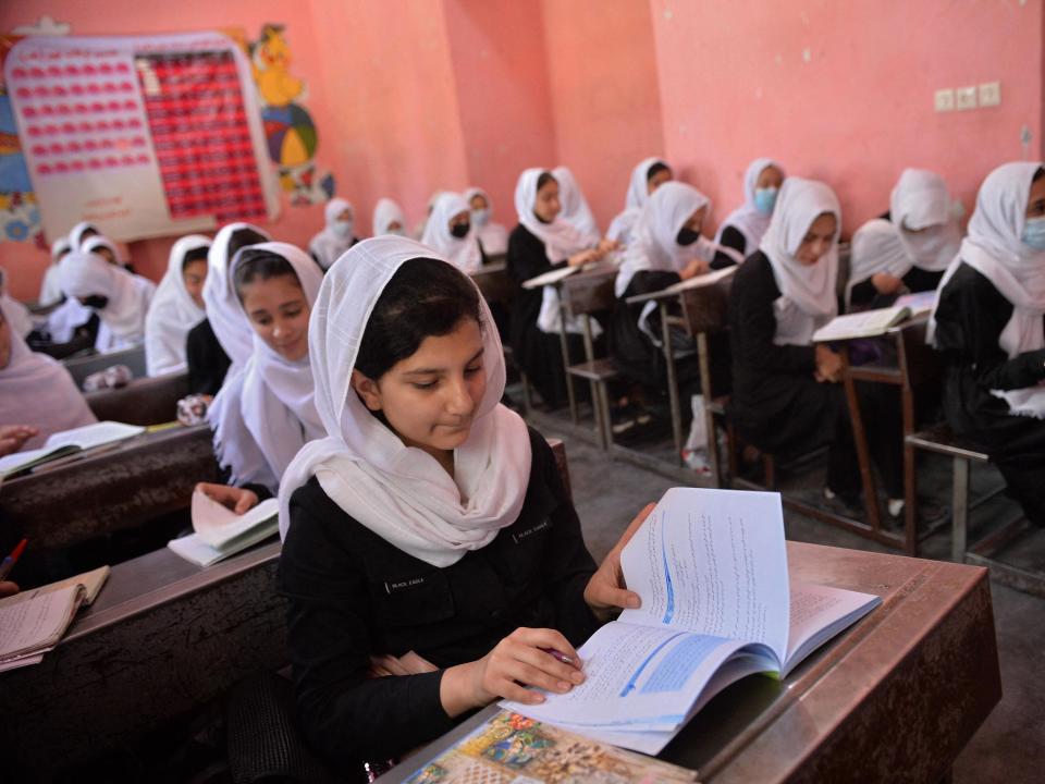 Girls in Afghanistan sit at desks in school.