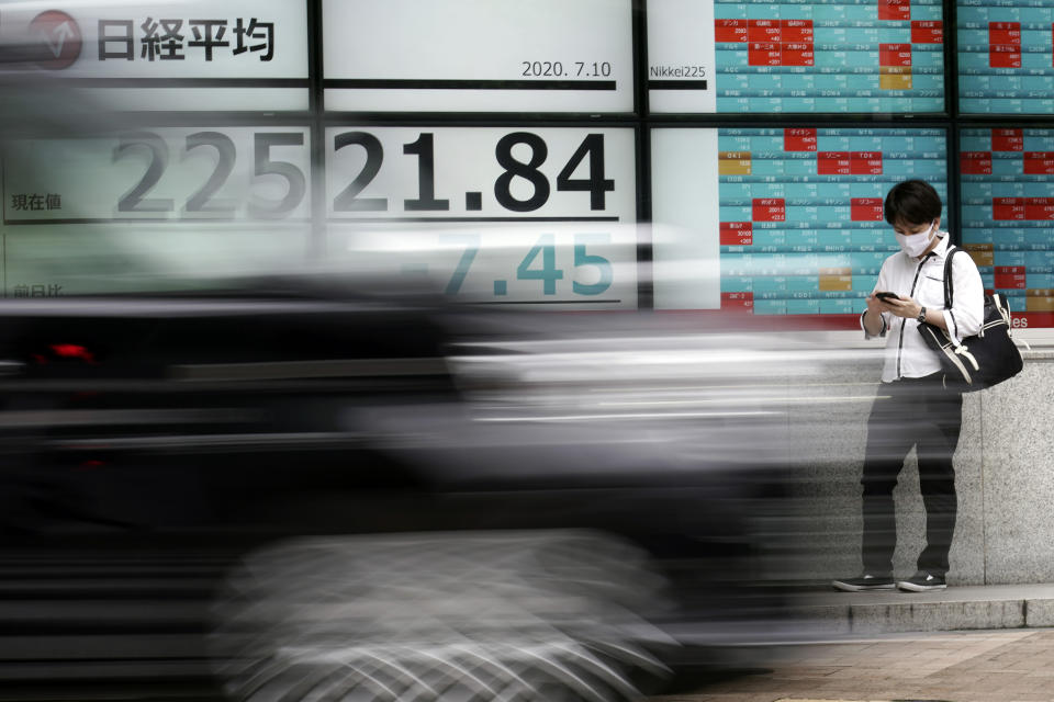 A man stands near an electronic stock board showing Japan's Nikkei 225 index at a securities firm as a car passing bay in Tokyo Friday, July 10, 2020. Asian stock markets followed Wall Street lower Friday on worries economic improvements might fade as coronavirus cases increase in the United States and some other countries. (AP Photo/Eugene Hoshiko)