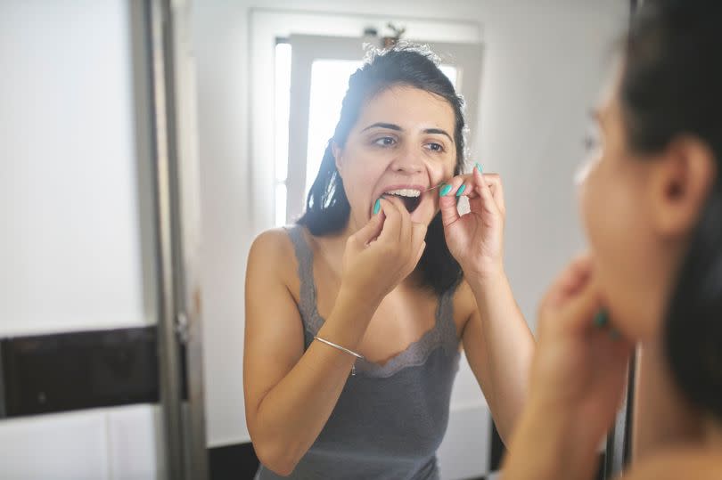 Young woman using dental floss.