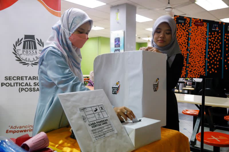 Hajar Wahab monitors her fellow undergraduate cast a vote during a mock-up election for Malaysia's upcoming general election at Gombak