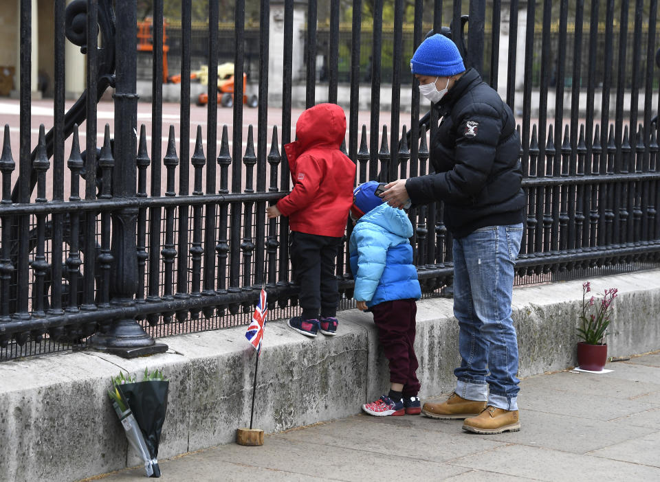 A child peers through the gates of Buckingham Palace in London, a day after the death of Britain's Prince Philip, Saturday, April 10, 2021. Britain's Prince Philip, the irascible and tough-minded husband of Queen Elizabeth II who spent more than seven decades supporting his wife in a role that mostly defined his life, died on Friday. (AP Photo/Alberto Pezzali)