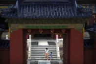 A woman and child wearing face masks to protect against the coronavirus walk through the Temple of Heaven in Beijing, Saturday, July 18, 2020. Authorities in a city in far western China have reduced subways, buses and taxis and closed off some residential communities amid a new coronavirus outbreak, according to Chinese media reports. They also placed restrictions on people leaving the city, including a suspension of subway service to the airport. (AP Photo/Mark Schiefelbein)