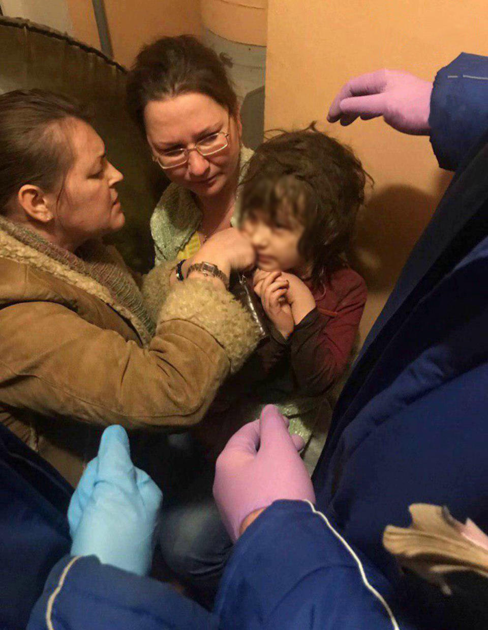 Neighbours try to remove the necklace that rooted into the girl’s skin. The five-year-old dubbed ‘Mowgli’ girl was found in an apartment in Russia. Source: east2west/Australscope