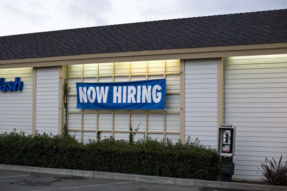 a restaurant exterior with a "now hiring" banner