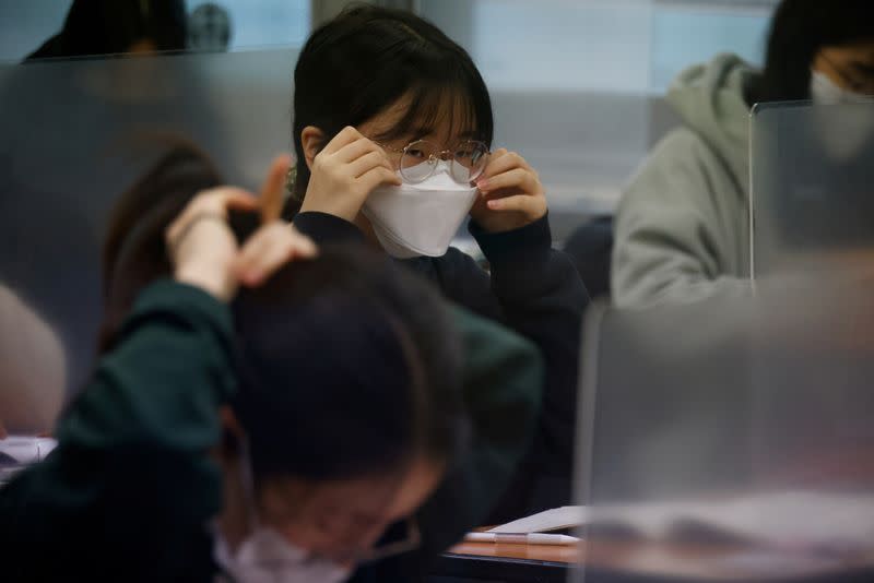 A student adjust her mask ahead of the annual college entrance examinations amid the coronavirus disease (COVID-19) pandemic at an exam hall in Seoul