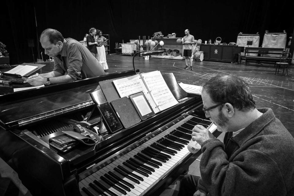 Conductor Gregory Buchalter, left, checks his phone and pianist Paul Schwartz takes in a quick read during a short break as director Jeffrey Marc Buchman (rear-left) and Kearstin Piper Brown (rear-center) rehearse with cast members of ‘I pagliacci’ at the Balfe Rehearsal Hall in Doral, Florida. Carl Juste/cjuste@miamiherald.com