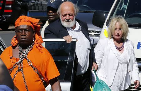 A protester with chains (L) looks on as Barry (C) and June Steenkamp, the parents of Reeva Steenkamp, arrive ahead of South African Olympic and Paralympic sprinter Oscar Pistorius' sentencing at the North Gauteng High Court in Pretoria October 21, 2014. REUTERS/Siphiwe Sibeko