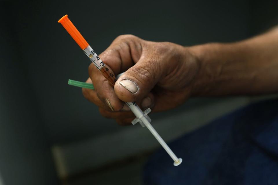 A hand holding a syringe with an orange cap