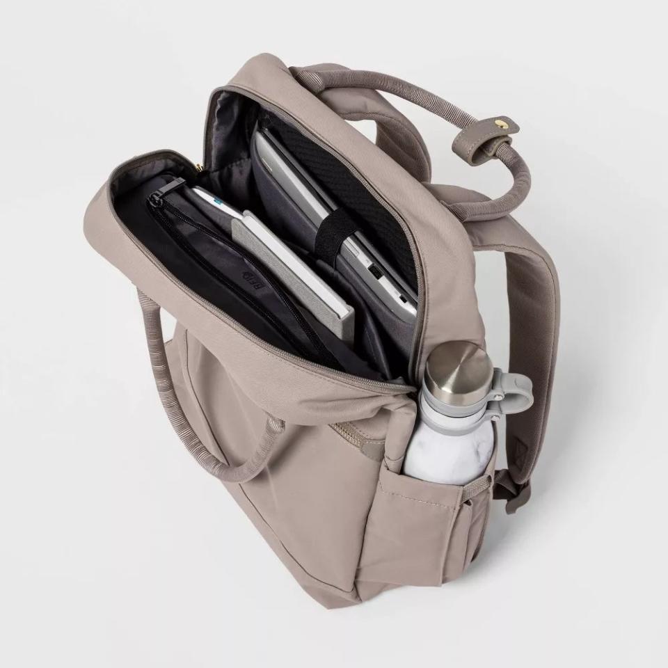 The backpack in the color Taupe, open at the top to show what's been stored inside