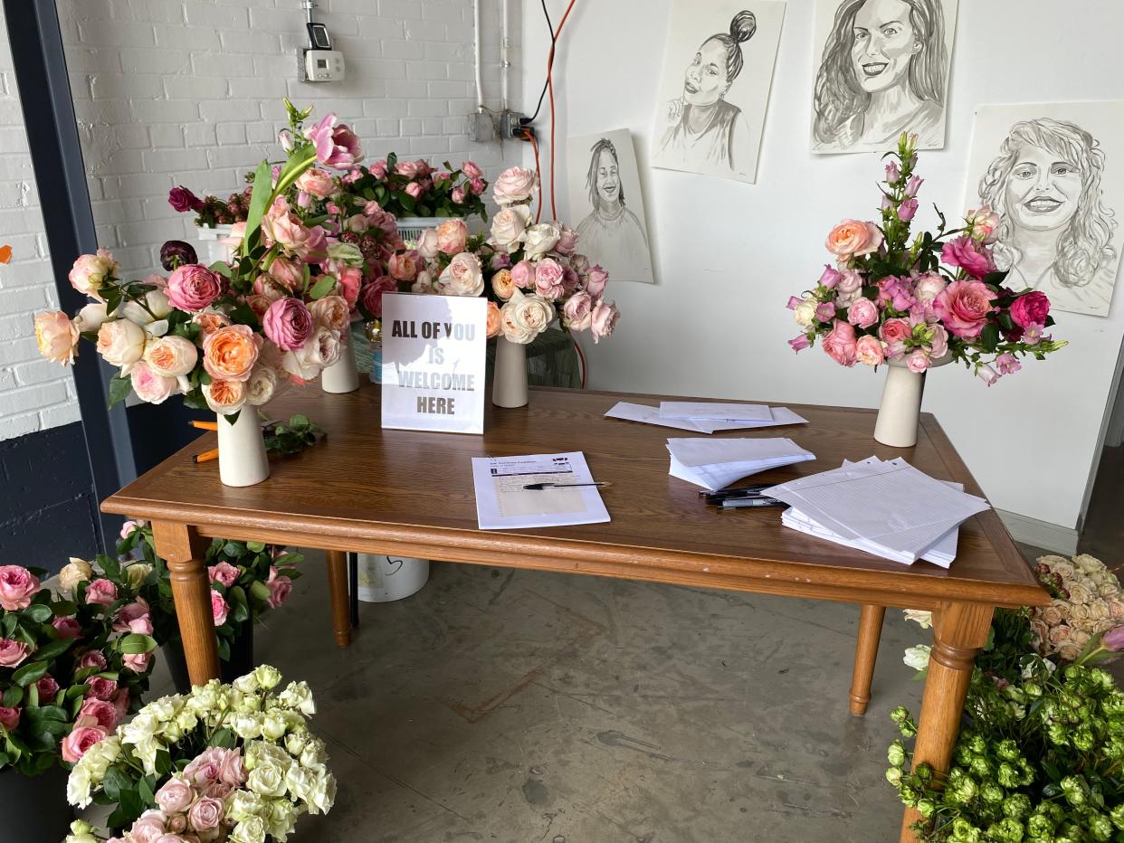 A table at The Wild Mother's Send Flowers to Survivors floral installation event invites guests to write letters to criminalized survivors of domestic violence.