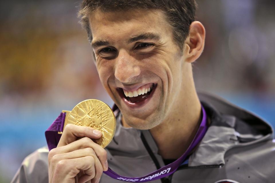 FILE - In this Aug. 3, 2012, file photo, United States' Michael Phelps displays his gold medal for the men's 100-meter butterfly swimming final at the Aquatics Centre in the Olympic Park during the 2012 Summer Olympics in London. Phelps is coming out of retirement, the first step toward possibly swimming at the 2016 Rio Olympics. Bob Bowman, the swimmer's longtime coach, told The Associated Press on Monday, April 14, 2014, that Phelps is entered in three events — the 50- and 100-meter freestyles and the 100 butterfly at his first meet since the 2012 London Games at a meet in Mesa, Ariz., on April 24-26. (AP Photo/Matt Slocum, File)