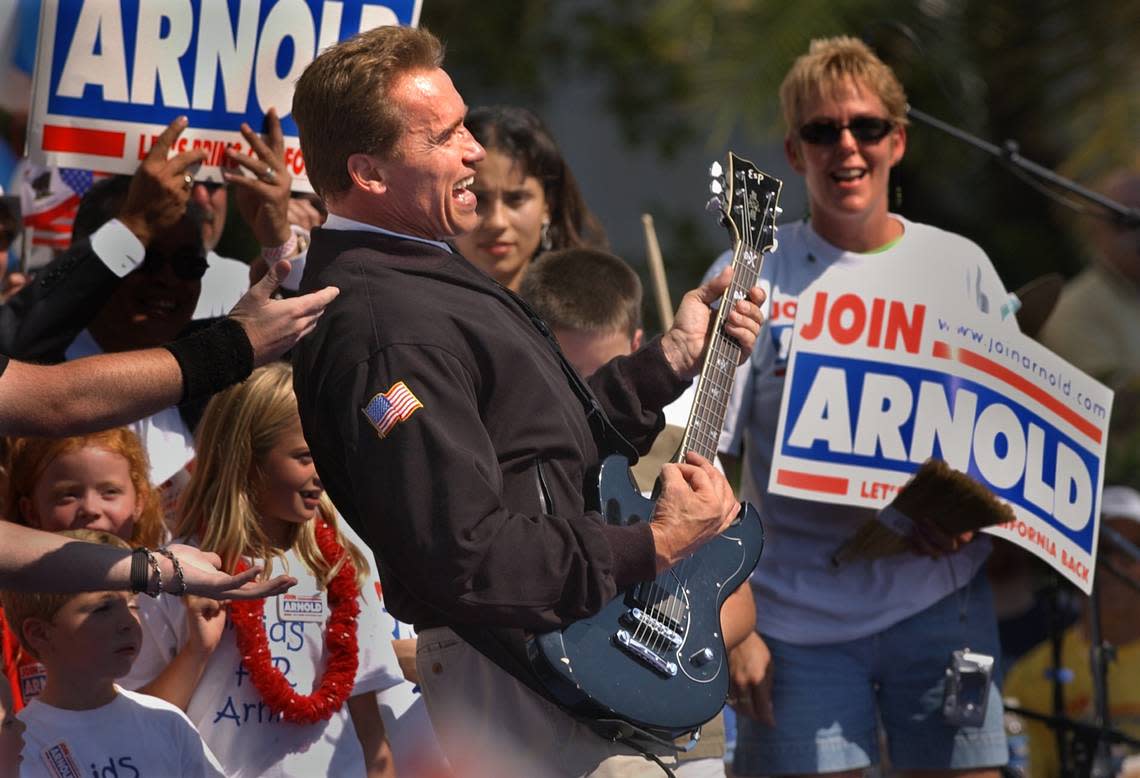 Republican gubernatorial candidate Arnold Schwarzenegger pretends to play the guitar after a member of the band Twisted Sister handed him the instrument during a rally at the state Capitol on Oct. 5, 2003. RANDY PENCH/Sacramento Bee file