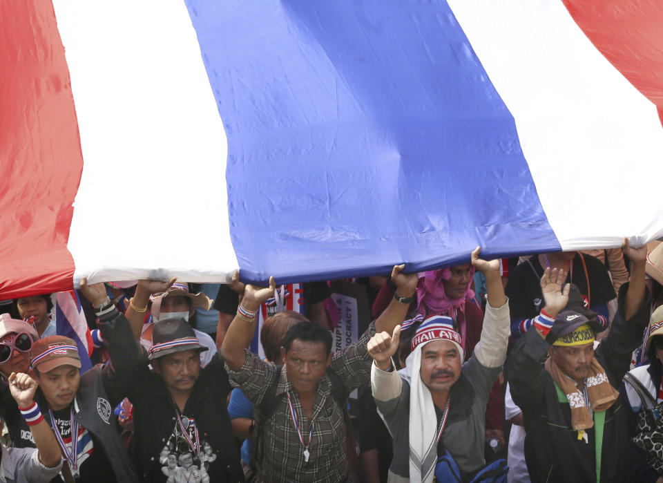 Thai anti-government protesters hold a giant national flag and march during a rally in Bangkok, Thailand, Saturday, Jan. 25, 2014. Thailand's ruling party has questioned the reasoning behind a court decision allowing next month's general election to be postponed, but held open the possibility that it might agree to put off the polls if its political rivals agree to recognize the legitimacy of a new vote. (AP Photo/Apichart Weerawong)