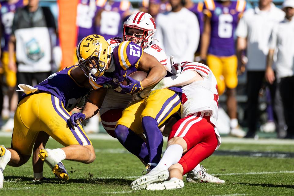 Wisconsin Badgers linebacker C.J. Goetz (98) and safety Hunter Wohler tackle LSU running back Josh Williams during the second half at the Reliaquest Bowl.