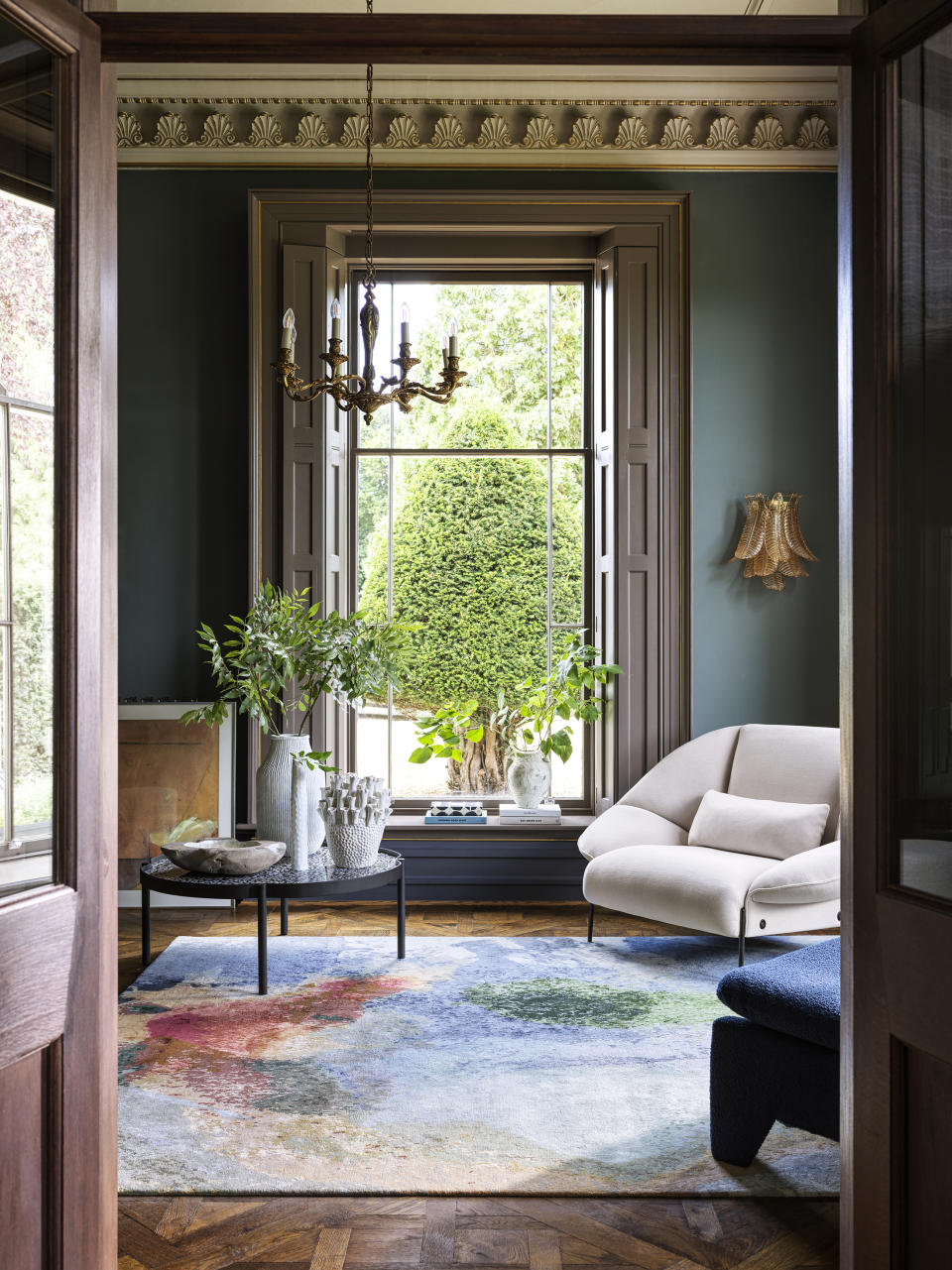 living room with large windows, white accent chair and coffee table, light blue rug