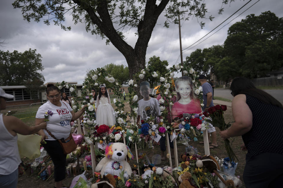 Dorina Davila, left, from San Antonio, places flowers at a memorial outside Robb Elementary School in Uvalde, Texas, Monday, May 30, 2022. In a town as small as Uvalde, even those who didn't lose their own child lost someone. Some say now that closeness is both their blessing and their curse: they can lean on each other to grieve. But every single one of them is grieving. (AP Photo/Wong Maye-E)