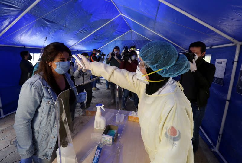 A medic checks the temperature of a woman inside a tent facility in Beirut's southern suburb