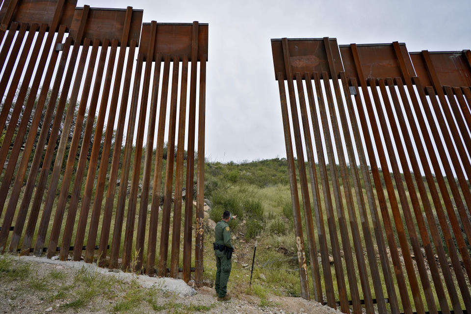 U.S. Border Patrol agent Jesus Vasavilbaso looks into Mexico at a breach in the 30-foot-high border wall where a gate was never installed due to a halt in construction, Thursday, Sept. 8, 2022, in Sasabe, Ariz. The wall, in a region at the base of the Baboquivari Mountains located in the Tucson sector, is one of the deadliest stretches along the international border with rugged desert mountains, uneven topography, washes and triple-digit temperatures in the summer months. Border Patrol agents performed 3,000 rescues in the sector in the past 12 months. (AP Photo/Matt York)