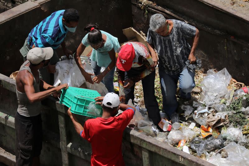 FILE PHOTO: People search for food in a garbage container during the closing hour at the Coche wholesale market during the coronavirus disease (COVID-19) outbreak, in Caracas