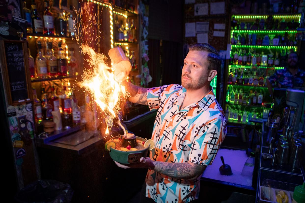 Jameson Cowman garnishes a flaming Scorpion Bowl at Monkey’s Paw Tiki Bar in Springfield.