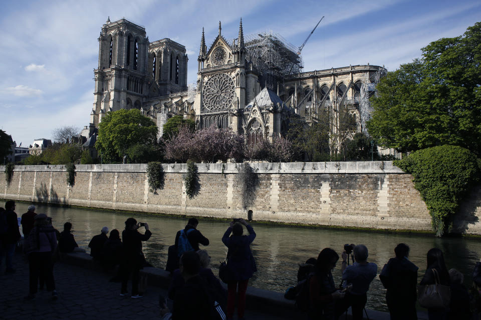 People watch Notre Dame cathedral, in Paris, Wednesday, April 17, 2019. Notre Dame Cathedral would have been completely burned to the ground in a "chain reaction collapse" had firefighters not moved rapidly in deploying their equipment to battle the blaze racing through the landmark monument, a Paris official said Wednesday. (AP Photo/Thibault Camus)