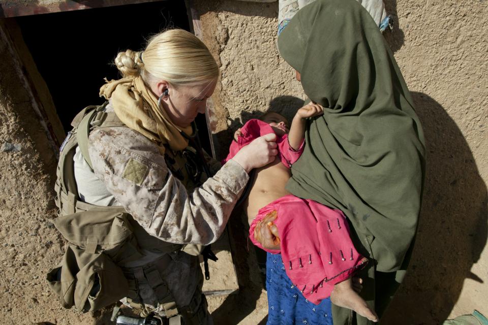 BOLDOC, AFGHANISTAN - NOVEMBER 23: (SPAIN OUT, FRANCE OUT, AFP OUT) Hospital Corpsman Amy Housley, 29, US Marine with the FET (Female Engagement Team) 1st Battalion 8th Marines, Regimental Combat team II checks the heartbeat of a sick child during a village medical outreach on November 23, 2010 in Boldoc, in Helmand province, Afghanistan. There are 48 women presently working along the volatile front lines of the war in Afghanistan deployed as the second Female Engagement team participating in a more active role, gaining access where men can't. The women, many who volunteer for the 6.5 month deployment take a 10 week course at Camp Pendleton in California where they are trained for any possible situation, including learning Afghan customs and basic Pashtun language. (Photo by Paula Bronstein/Getty Images)