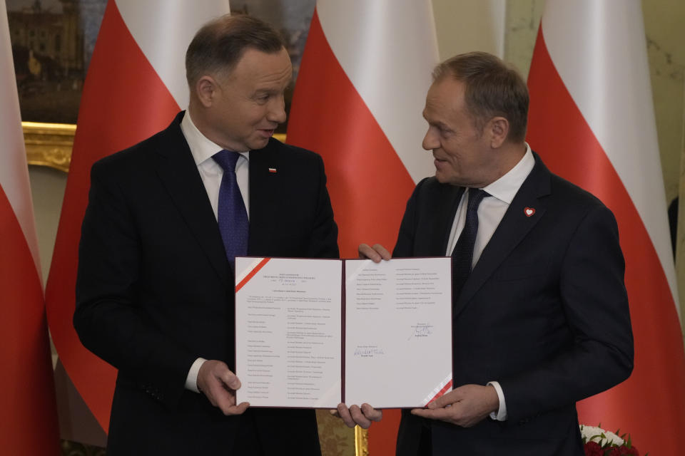 Poland's new Prime Minister Donald Tusk, right, and Poland's President Andrzej Duda pose for cameras during the swearing-in ceremony at the presidential palace in Warsaw, Poland, Wednesday, Dec. 13, 2023. Donald Tusk was sworn in by the president in a ceremony where each of his ministers was also taking the oath of office. (AP Photo/Czarek Sokolowski)