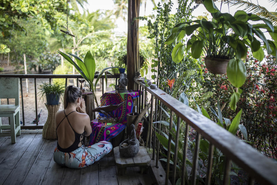 Un turista realiza un ritual con varias estatuillas, incluida una de una ballena, en el Jardín Botánico del Pacífico en Bahía Solano, Colombia, el martes 29 de agosto de 2023. (AP Foto/Iván Valencia)