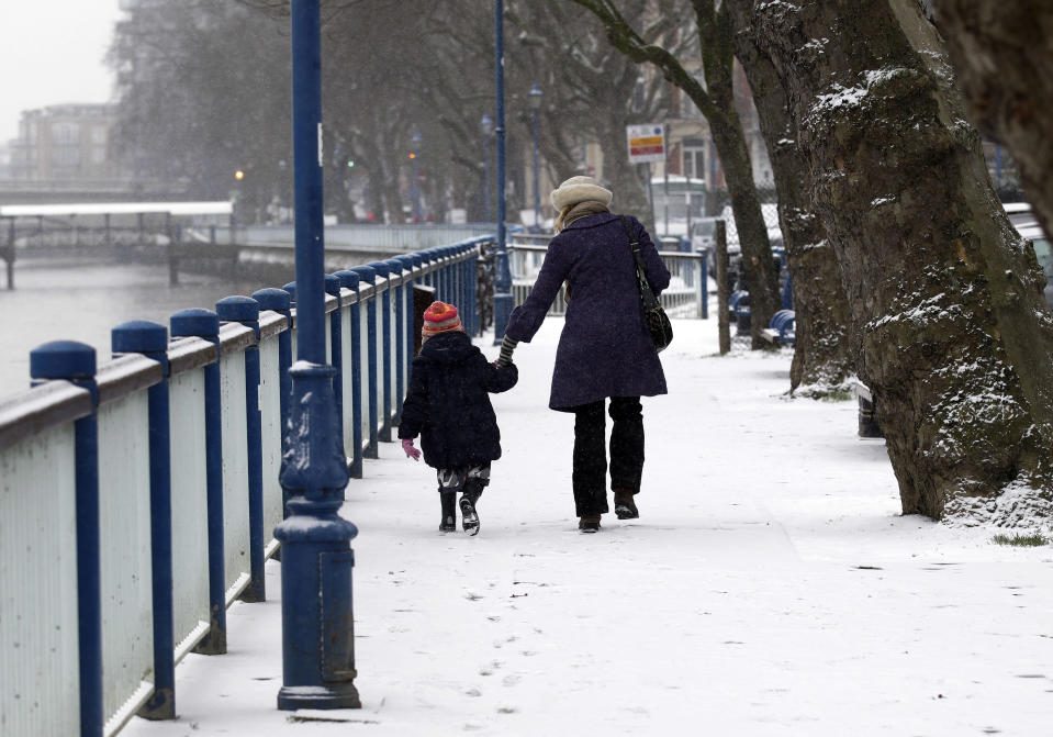 People walk along a snow covered embankment at Putney Bridge, in London, Sunday, Jan. 20, 2013. The big freeze across the UK is here to stay, with more snow expected next week. (AP Photo/Sang Tan)