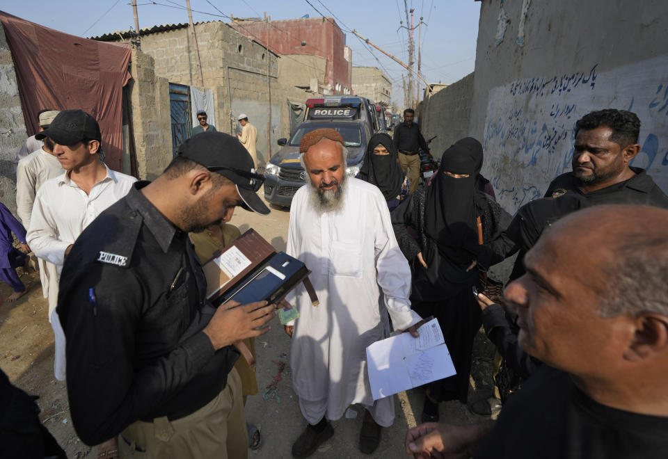 FILE - A police officer checks the document of a resident during a search operation against illegal immigrants at a neighborhood of Karachi, Pakistan, Friday, Nov. 3, 2023. Early the previous month, Pakistan announced a major crackdown on foreigners living in the country illegally, including around 1.7 million Afghans. (AP Photo/Fareed Khan, File)