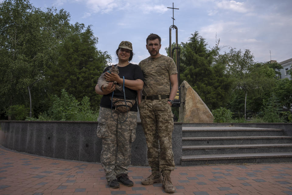 Soldier Valentyna with her cat and partner Vitalii, right, take a walk in the main square of Kramatorsk, Ukraine, Tuesday, July 5, 2022. The couple just returned from the frontlines of Lysychansk to take some time off. They are planning to return to fight. (AP Photo/Nariman El-Mofty)