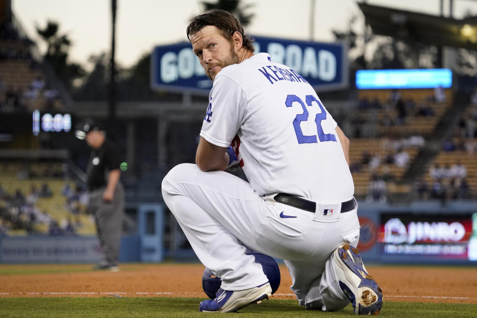 Los Angeles Dodgers' Clayton Kershaw kneels at first as he waits for a pitching change during the third inning of a baseball game against the Texas Rangers Friday, June 11, 2021, in Los Angeles. (AP Photo/Mark J. Terrill)
