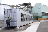 A state worker closes a container holding processors used for bitcoin calculations at the La Geo Geothermal Power Plant in Berlin municipality, Usulutan department, El Salvador, Friday, Oct. 15, 2021. The government announced that it has installed 300 processors at this plant to "mine" cryptocurrency, and is using geothermal resources from the country’s volcanos to run the computers that perform the calculations to verify transactions in bitcoin, recently made legal tender. (AP Photo/Salvador Melendez)