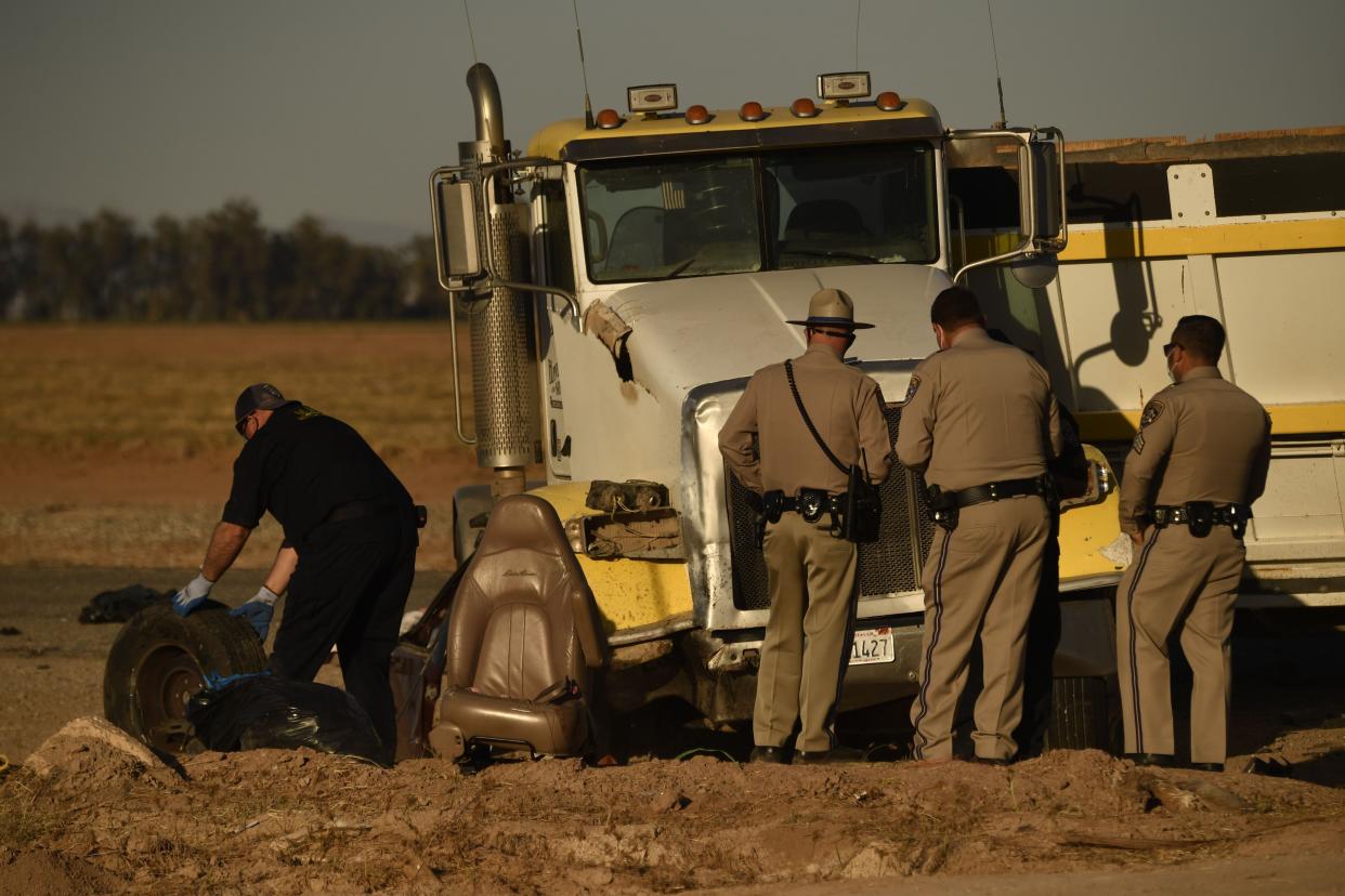 Investigators and California Highway Patrol Border Division officers look over the scene of a crash between an SUV and a semi-truck full of gravel near Holtville, Calif. on March 2, 2021.
