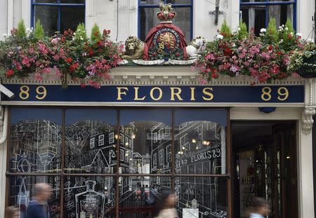 Shoppers walk past the shopfront of Floris with a royal warrant design above it in central London, Britain, August 19, 2015. Floris, established in 1730, holds a warrant as perfumer to Queen Elizabeth. Every year Queen Elizabeth grants about 20 royal warrants, the gold emblem of the British monarchy, in a practice dating back to medieval times. REUTERS/Toby Melville
