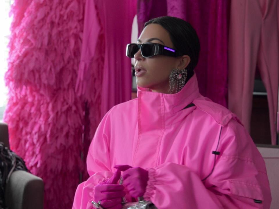 kim kardashian sitting in a bright pink jumpsuit and sunglasses on the kardashians