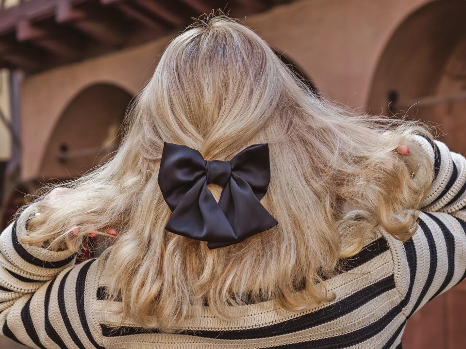 back of a blonde woman's head wearing a big black satin bow