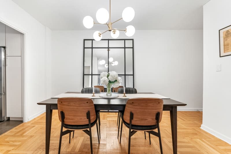 White dining room with wood floors, sputnik-style pendant light, and large mirror