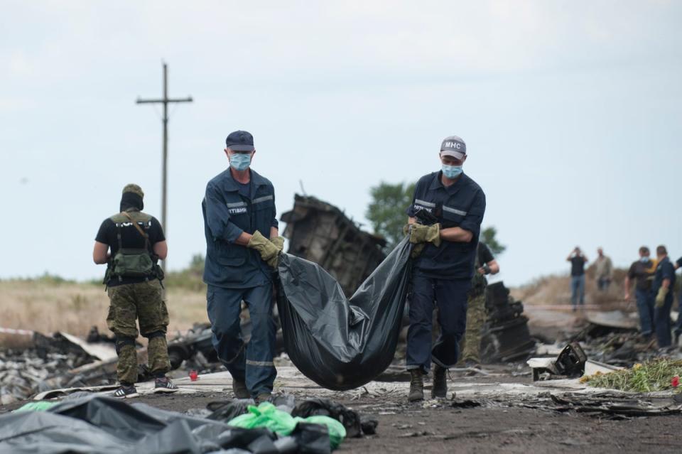 Emergency workers carry a body away from the crash scene (Copyright 2014 The Associated Press. All rights reserved)