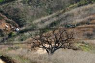 Personnel collect debris while working with NTSB investigators, right, at the helicopter crash site of NBA star Kobe Bryant in Calabasas, California