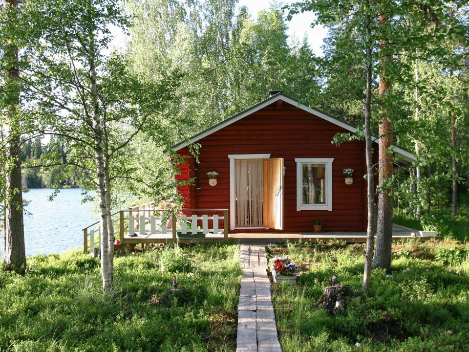 A red lakeside cabin in the woods.