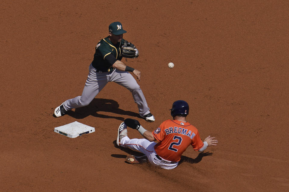 Oakland Athletics second baseman Tommy La Stella, top, throws to first base after forcing out Houston Astros' Alex Bregman at second base during the first inning of Game 3 of a baseball American League Division Series in Los Angeles, Wednesday, Oct. 7, 2020. (AP Photo/Marcio Jose Sanchez)