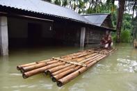 A villager sit on a makeshift bamboo raft near his partially submerged house following flood due to monsoon rain at a village in Nagaon District of Assam. (Photo credit should read Anuwar Ali Hazarika/Barcroft Media via Getty Images)