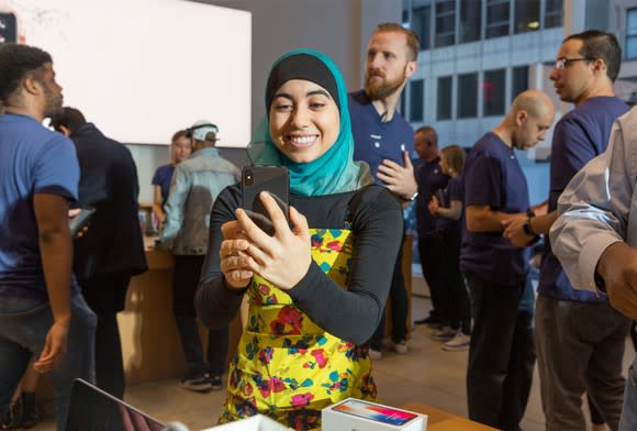 A woman holding an iPhone X inside of an Apple store.