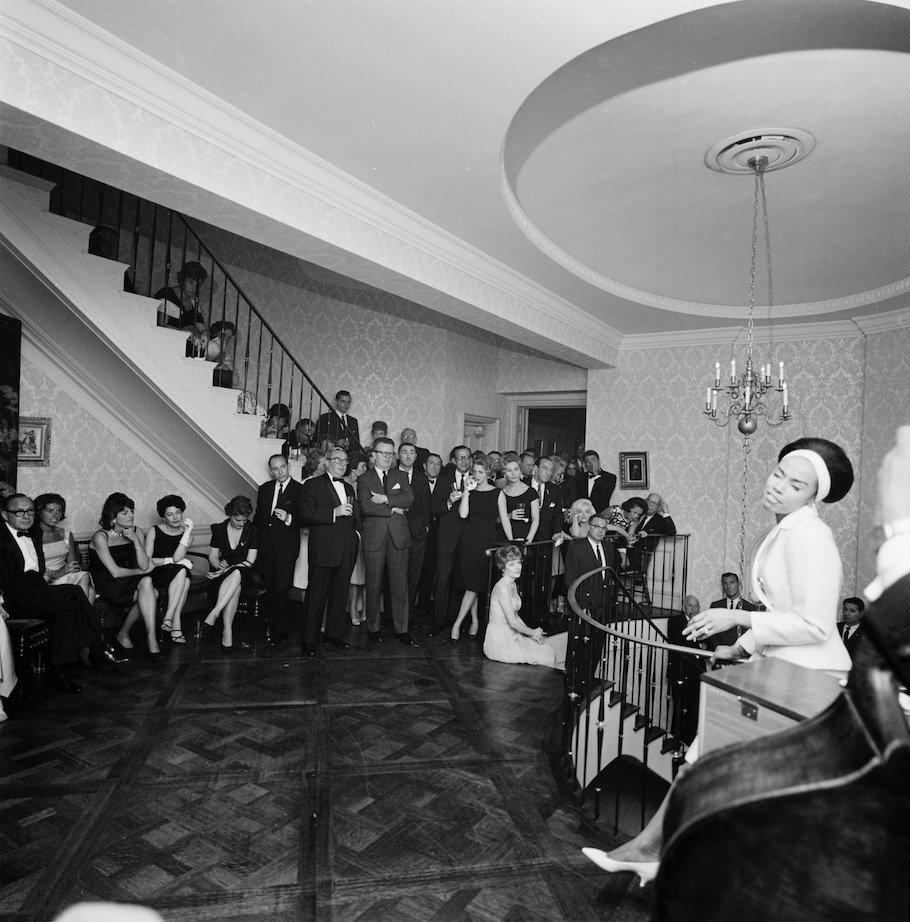 Diahann Carroll (far right), performs during an evening reception at the residence of Arthur B. Krim and Dr. Mathilde Krim in New York City, New York. Marilyn Monroe can be seen in the background.