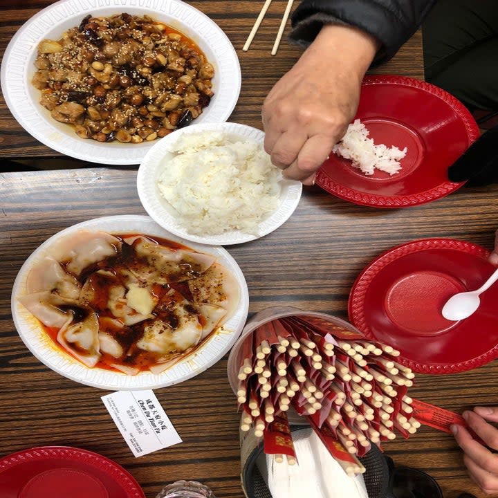 Hands digging into Chinese food