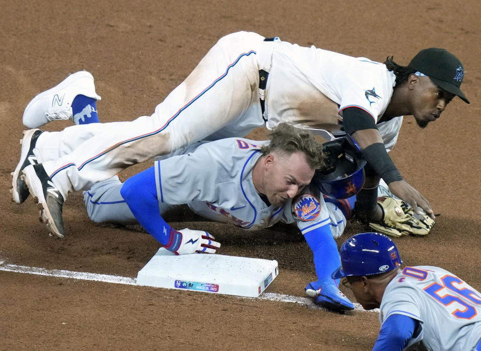 New York Mets' Brandon Nimmo, bottom left, collides with Miami Marlins third baseman Jean Segura, top, as he is safe at third on a single hit by Starling Marte (not shown) during the sixth inning of an opening day baseball game, Thursday, March 30, 2023, in Miami. (AP Photo/Lynne Sladky)