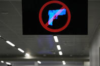 A television displays a "no guns" sign at the Transportation Security Administration security area at the Hartsfield-Jackson Atlanta International Airport on Wednesday, Jan. 25, 2023, in Atlanta. Last year saw a record number of guns intercepted at airport checkpoints across the country. The numbers have been steadily climbing and hit 6,542 last year. The head of the Transportation Safety Administration, David Pekoske, says this is a reflection of what is going on in society and in “society there are more people carrying firearms.” (AP Photo/Brynn Anderson)